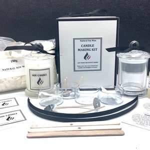 May include: A candle making kit with natural soy wax, a glass jar, wicks, and a bottle of fragrance oil. The kit includes instructions and labels for making candles. The kit is packaged in a black box with a white label that says "Natural Soy Wax Candle Making Kit".