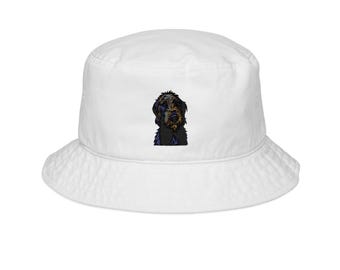 Puede incluir: Sombrero de pescador blanco con un diseño de perro negro y marrón. El sombrero tiene un ala ancha y un estilo relajado. El diseño del perro está centrado en la parte delantera del sombrero.