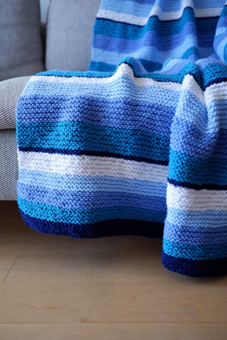 May include: A blue and white striped knitted throw blanket draped over a couch.