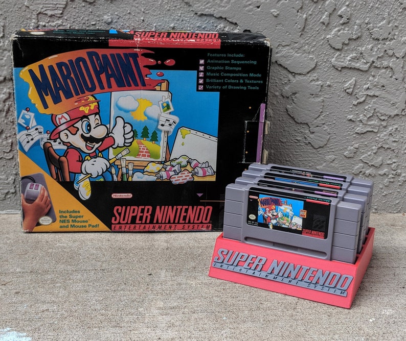 May include: A Super Nintendo game cartridge for Mario Paint, a classic video game that allows users to create and share their own artwork. The game cartridge is in its original packaging, which features a colorful illustration of Mario painting. The packaging also includes a description of the game's features, such as animation sequencing, graphic stamps, and music composition mode.