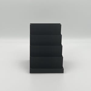 May include: Black plastic desktop organizer with five tiers for storing office supplies.