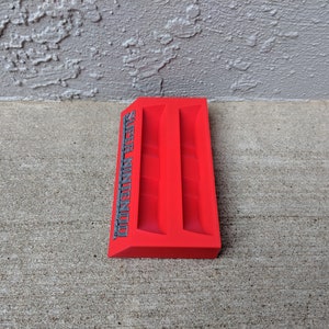 May include: Red plastic Super Nintendo game cartridge holder with two slots. The holder has the words "Super Nintendo" printed on the side in gray.