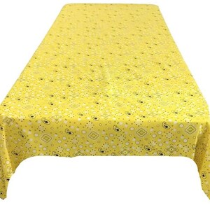 May include: A yellow tablecloth with a paisley pattern. The tablecloth is rectangular and has a repeating design of white and black paisley shapes, dots, and geometric patterns. The fabric is a bright yellow color.