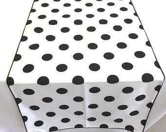 May include: White table runner with a black polka dot pattern. The runner has a black border.