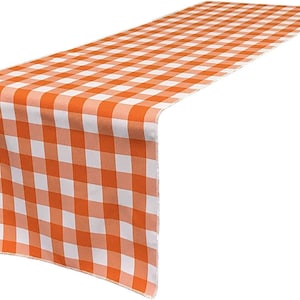 May include: Orange and white checkered table runner. The runner features a classic gingham pattern, perfect for adding a touch of rustic charm to any dining table or event. The fabric is a vibrant orange and white.