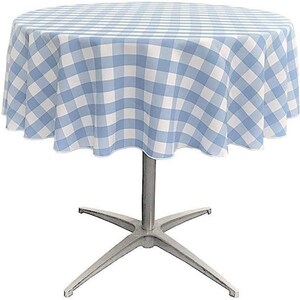 May include: A round table covered with a light blue and white gingham checkered tablecloth. The table features a central silver-colored metal pedestal base that branches out into four legs at the bottom, providing a stable support structure.