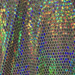 May include: Close-up of a shimmering, iridescent fabric with a honeycomb pattern. The fabric reflects a spectrum of colors, including green, blue, and orange, creating a dazzling effect. The material appears to be lightweight and flexible.