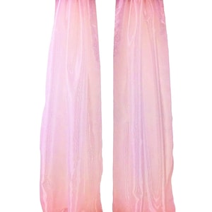 May include: Two sheer, pink curtains hang from a black rod. The curtains have a gradient effect, transitioning from a lighter pink at the top to a deeper pink at the bottom. The fabric appears lightweight and flowing, creating a soft, romantic aesthetic.