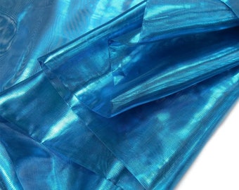 May include: Close-up of a vibrant, shimmering turquoise fabric. The material is folded, creating layers that reflect light, giving it a glossy appearance. The fabric's texture is visible, suggesting a lightweight, possibly sheer material.