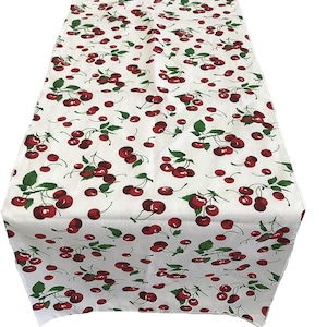 May include: White table runner with a red cherry pattern. The cherries are on green stems with leaves.