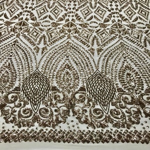 May include: Ivory fabric with an intricate pattern of bronze sequins. The design features geometric shapes and ornate, symmetrical motifs. The sequins create a shimmering effect, adding texture and visual interest to the textile. Suitable for apparel and decorative projects.