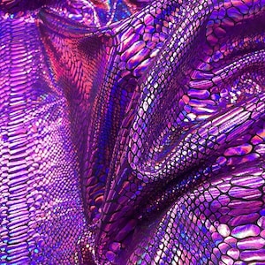 May include: A close-up of a vibrant, iridescent fabric with a snakeskin pattern. The fabric is a deep purple with highlights of pink, blue, and silver, creating a shimmering effect. The texture appears smooth and slightly reflective.