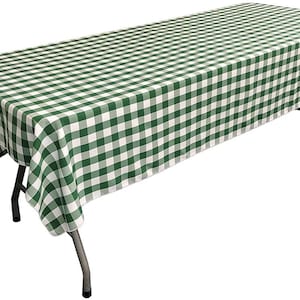 May include: Green and white checkered tablecloth with a white background and green squares. The tablecloth is draped over a table with metal legs.