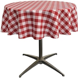 May include: A round table covered with a red and white checkered tablecloth. The fabric features a classic gingham pattern with alternating square blocks. The table is supported by a central metal pedestal base with four extending legs.