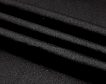 May include: Close-up of black fabric with visible folds and subtle texture. The fabric appears to be a solid color, with a matte finish. The folds create shadows and highlights, adding depth to the image. The fabric is likely used for clothing or home decor.