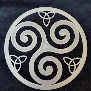 Peut inclure: Une décoration murale en métal argenté avec un design circulaire composé de trois spirales entrelacées et de trois nœuds celtiques.