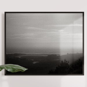 Könnte beinhalten: Ein Schwarzweißfoto einer Landschaft mit einem Fluss, der sich durch sie schlängelt. Der Himmel ist bewölkt und der Horizont ist in der Ferne.