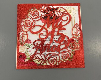 May include: Red glitter card with a cut-out design of roses and the text "Mis Quince Anos".