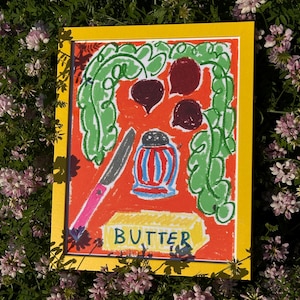 May include: A framed, colorful illustration with a yellow border. The artwork features a red background with green leafy elements, three dark red shapes, a salt shaker, a knife, and the word "BUTTER" in blue letters on a yellow rectangle.
