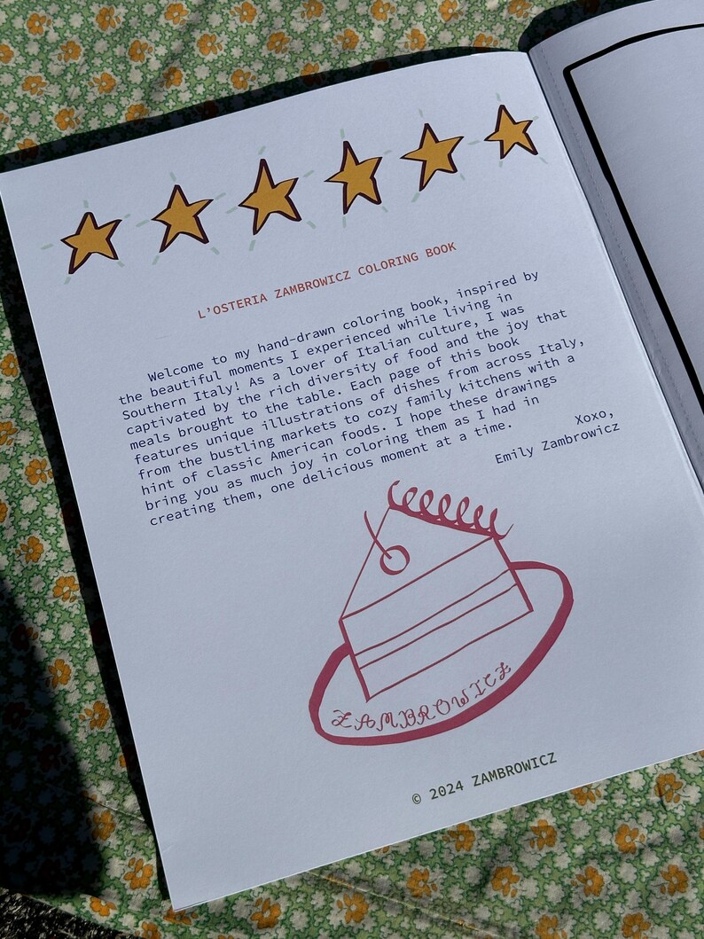 May include: Open coloring book page with text and illustrations. The title reads "L'Osteria Zambrowicz Coloring Book." The page includes a welcome message, a cake illustration, and the author's signature. The book is inspired by Italian culture and food.
