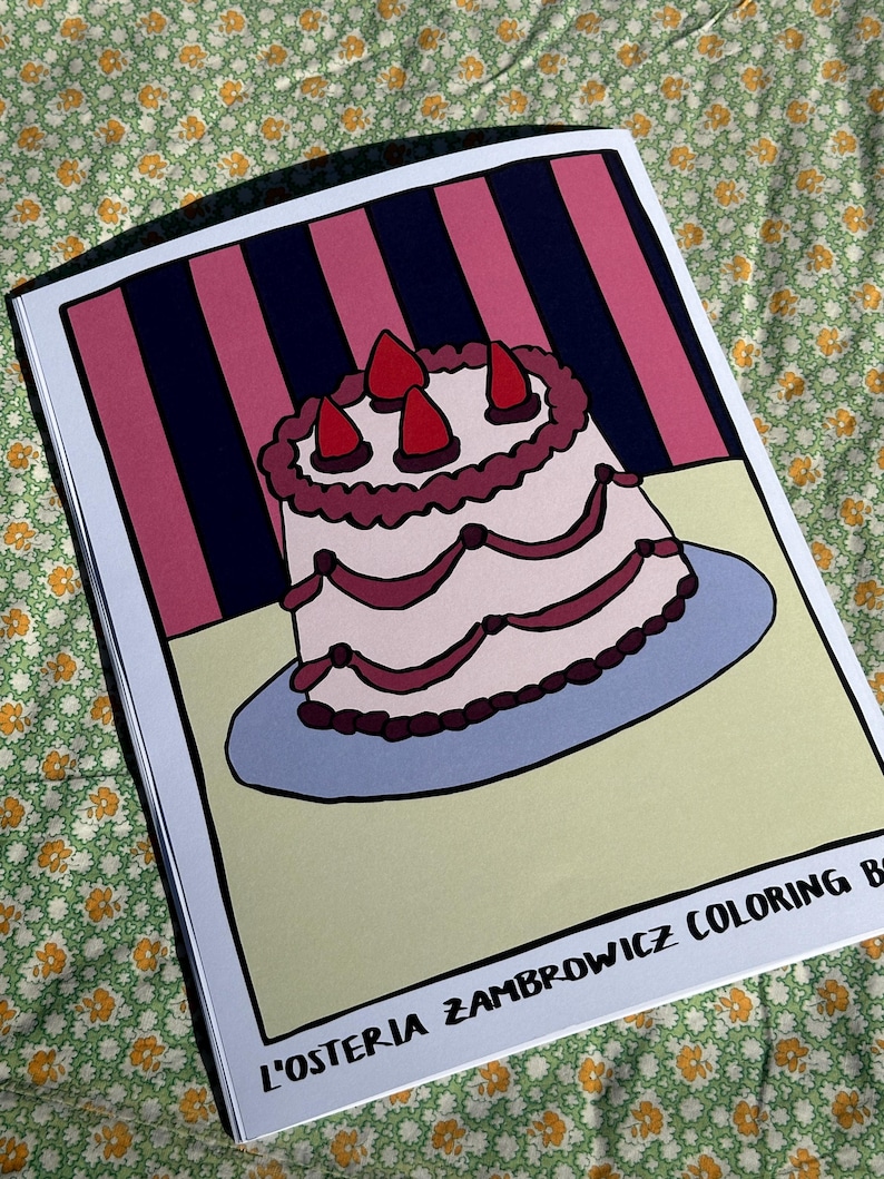 May include: A coloring book featuring a cartoon cake illustration with three strawberry toppings. The cake is on a blue plate, set against a pink and navy striped background. The book's title, "L'OSTERIA ZAMBROWICZ COLORING BOOK", is printed at the bottom.