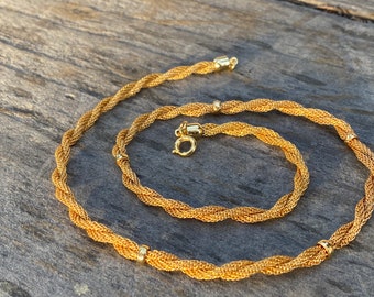 May include: A gold chain necklace and bracelet set with a twisted rope design. The necklace and bracelet have small round accents.