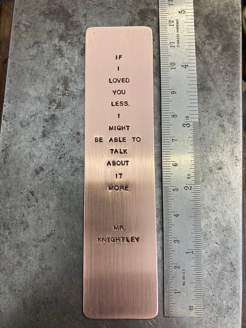 May include: A copper bookmark with the text "If I loved you less, I might be able to talk about it more. Mr. Knightley" engraved on it.