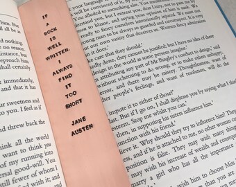 May include: A pink bookmark with the text "If a book is well written, always find it too short" and "Jane Austen" printed on it. The bookmark is placed on a page of a book with the text "Pride and Prejudice" visible.