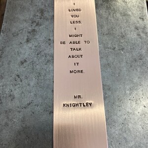 May include: A copper bookmark with the quote "If I loved you less, I might be able to talk about it more." inscribed on it. The quote is attributed to Mr. Knightley.