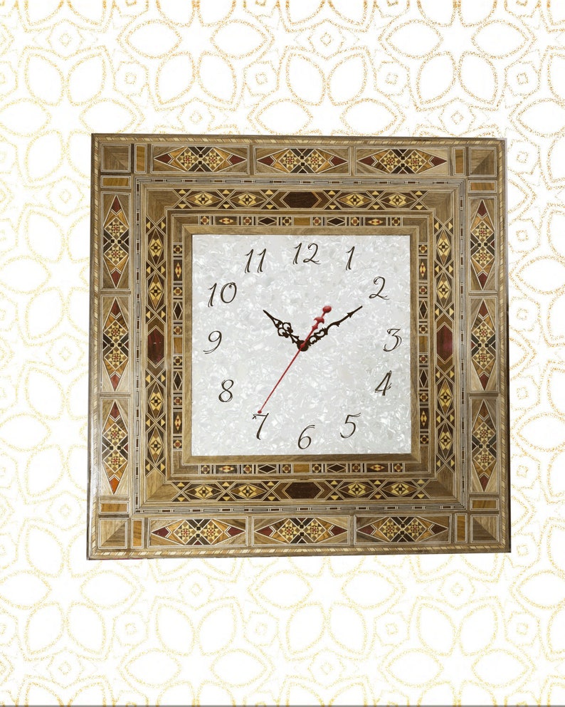 May include: A square clock with a white face and black Roman numeral hour markers. The clock is framed in a decorative wooden frame with intricate inlaid wood patterns in shades of brown, beige, and red.