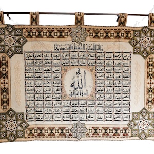 May include: A beige tapestry with a brown border and intricate geometric patterns. The centre features a large black Arabic inscription of the word "Allah" surrounded by smaller Arabic text.