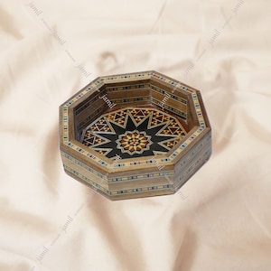 May include: Octagonal wooden bowl with a geometric inlay design in shades of brown, black, and white. The bowl has a starburst pattern in the center.