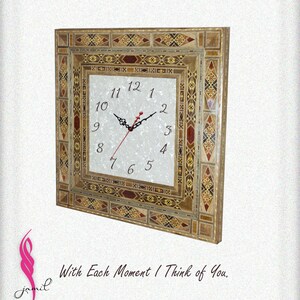 May include: A square clock with a white face and black hands, surrounded by a decorative frame made of inlaid wood in shades of brown, red, and gold. The frame has a geometric pattern.