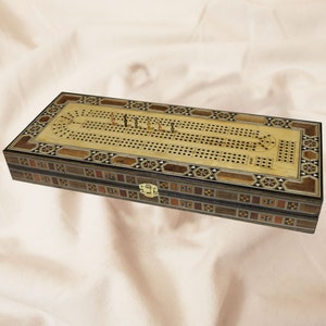 May include: A wooden backgammon game set with a traditional inlaid design. The game board is open and shows the playing pieces in place. The set is closed in a wooden box with a latch.