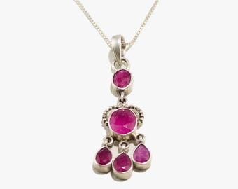 May include: A silver necklace with a pink gemstone pendant. The pendant features a large round stone surrounded by smaller stones.