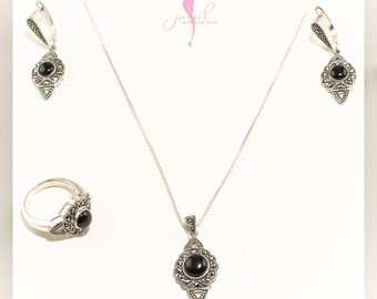 May include: A silver necklace, ring, and earrings set with black onyx stones and marcasite accents. The jewelry is displayed on a white background.