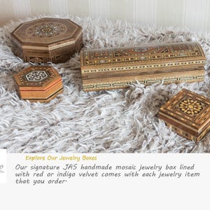 May include: Four intricately carved wooden jewelry boxes with inlaid mosaic patterns. The boxes are various shapes and sizes, including a rectangular box, a square box, and two octagonal boxes. The boxes are displayed on a white fluffy surface.