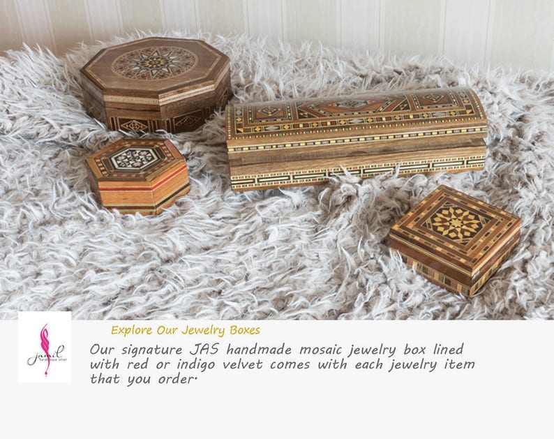 May include: Four intricately carved wooden jewelry boxes with inlaid mosaic patterns. The boxes are various shapes and sizes, including a rectangular box, a square box, and two octagonal boxes. The boxes are displayed on a white fluffy surface.
