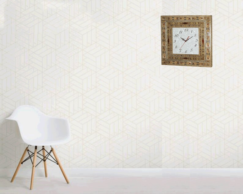 May include: A square clock with Roman numerals and a white face. The clock is framed in a decorative wood frame with inlaid designs in various colors. The clock is hanging on a white wall with a geometric pattern.