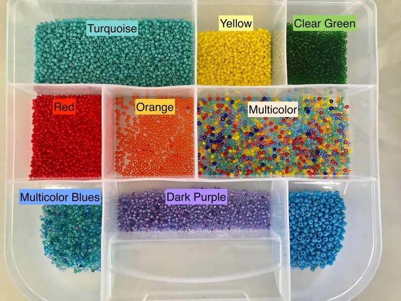 May include: A clear plastic storage box with multiple compartments filled with colourful seed beads. The compartments are labelled with the colours of the beads: Turquoise, Yellow, Clear Green, Red, Orange, Multicolour, Multicolour Blues, Dark Purple, and Blue.