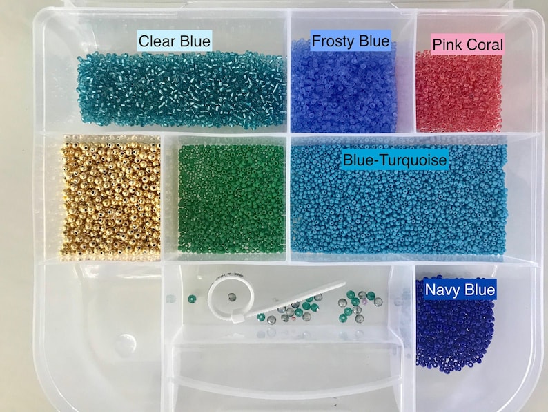 May include: A clear plastic storage box with 10 compartments filled with various colours of seed beads. The compartments are labelled with the bead colours: Clear Blue, Frosty Blue, Pink Coral, Blue-Turquoise, and Navy Blue.