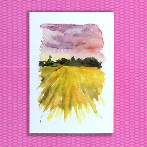 May include: Watercolor painting of a field of yellow wheat with a purple and pink cloudy sky in the background.