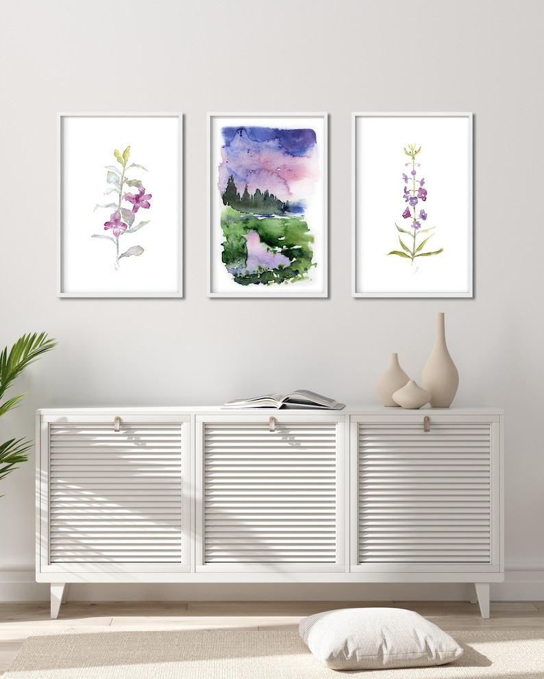 Pode incluir: Tr&ecirc;s pinturas em aquarela emolduradas de temas bot&acirc;nicos. A obra de arte inclui um arranjo floral roxo e verde, uma paisagem com um c&eacute;u roxo e azul e uma flor roxa e verde. As pinturas s&atilde;o exibidas acima de um arm&aacute;rio branco.