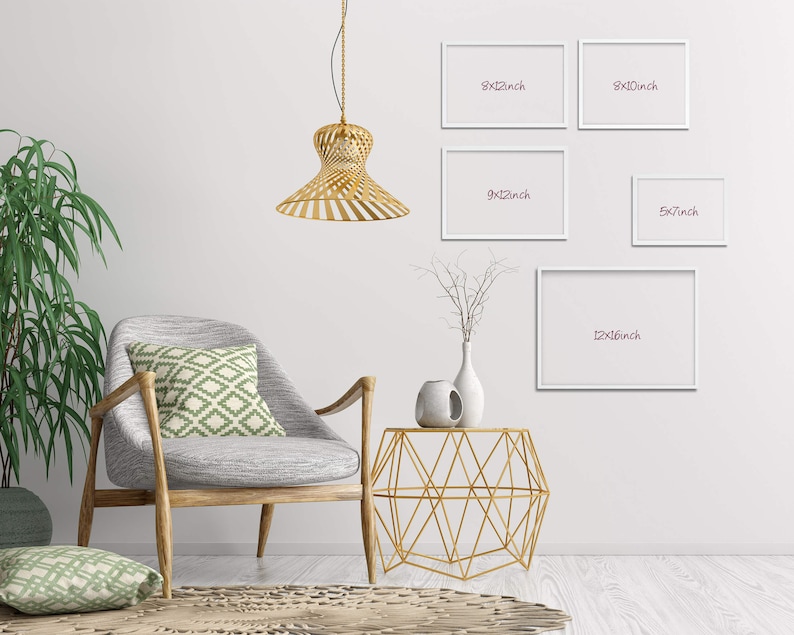 May include: A white wall with five white picture frames of different sizes. The frames are hanging on the wall. The frames are labeled with their dimensions in inches. A gold geometric side table with a white vase and a gold pendant light are in the foreground.