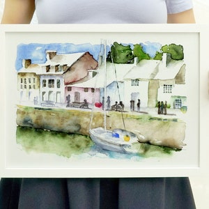 May include: Watercolor painting of a small town harbor with colorful buildings, a sailboat, and people walking along the waterfront.