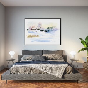 May include: A watercolor painting of a snowy landscape with a small house in the distance. The painting is framed in black and hanging on a gray wall above a gray bed with a gray blanket and pillows. There are two white lamps on black side tables next to the bed. A potted plant is on the right side of the image.