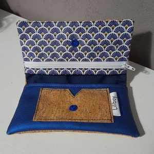 May include: A blue and cork wallet with a blue button closure. The interior lining features a blue and white fan pattern. The wallet has a white zipper and a small label that says "Liliboy".