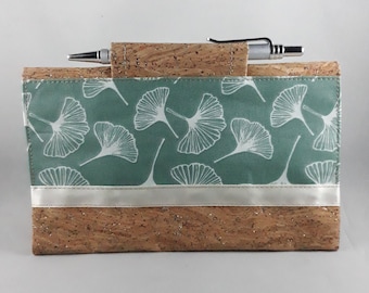 May include: A rectangular cork notebook cover with a pen holder. The cover features a teal fabric panel with white ginkgo leaf patterns and a silver ribbon accent. A silver pen rests in the holder, ready for use.