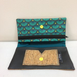 May include: Open black wallet with a teal and green patterned interior. The wallet has a zippered pocket and a cork pocket with a yellow snap closure. The brand name "Liliboy" is visible on a small tag.