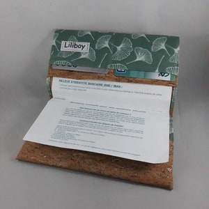 May include: A wallet with a cork base and a green fabric top featuring a white leaf pattern. The wallet is open, revealing a paper document and card slots. The text "Liliboy" is visible on the top.